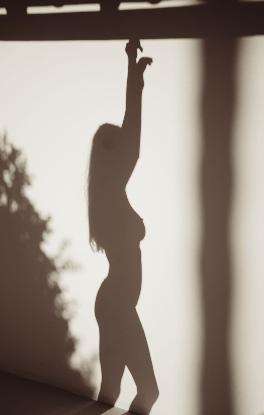 Silhouette of a woman reaching upward into the light