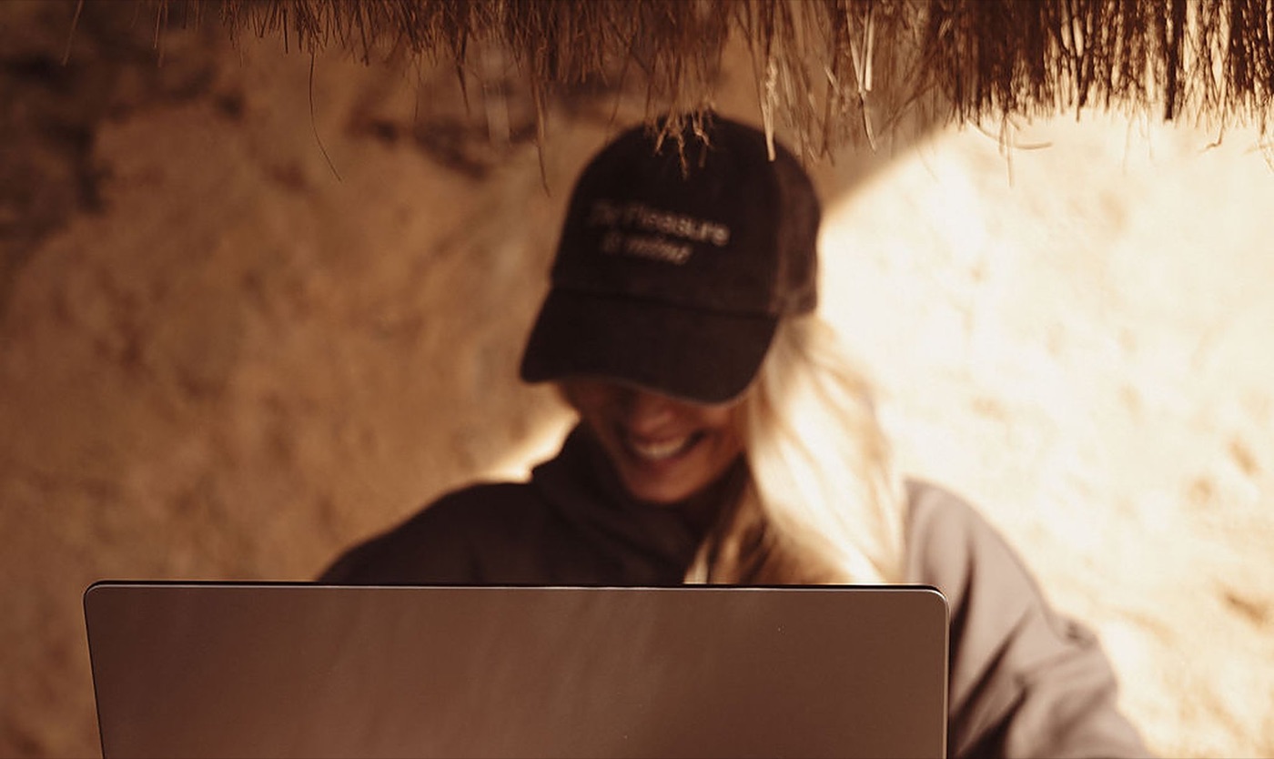 Lächelnde Frau am Laptop in einer gemütlichen, privaten Ecke – ein Online-Intimitätskurs zu Hause im eigenen Tempo | My Temple