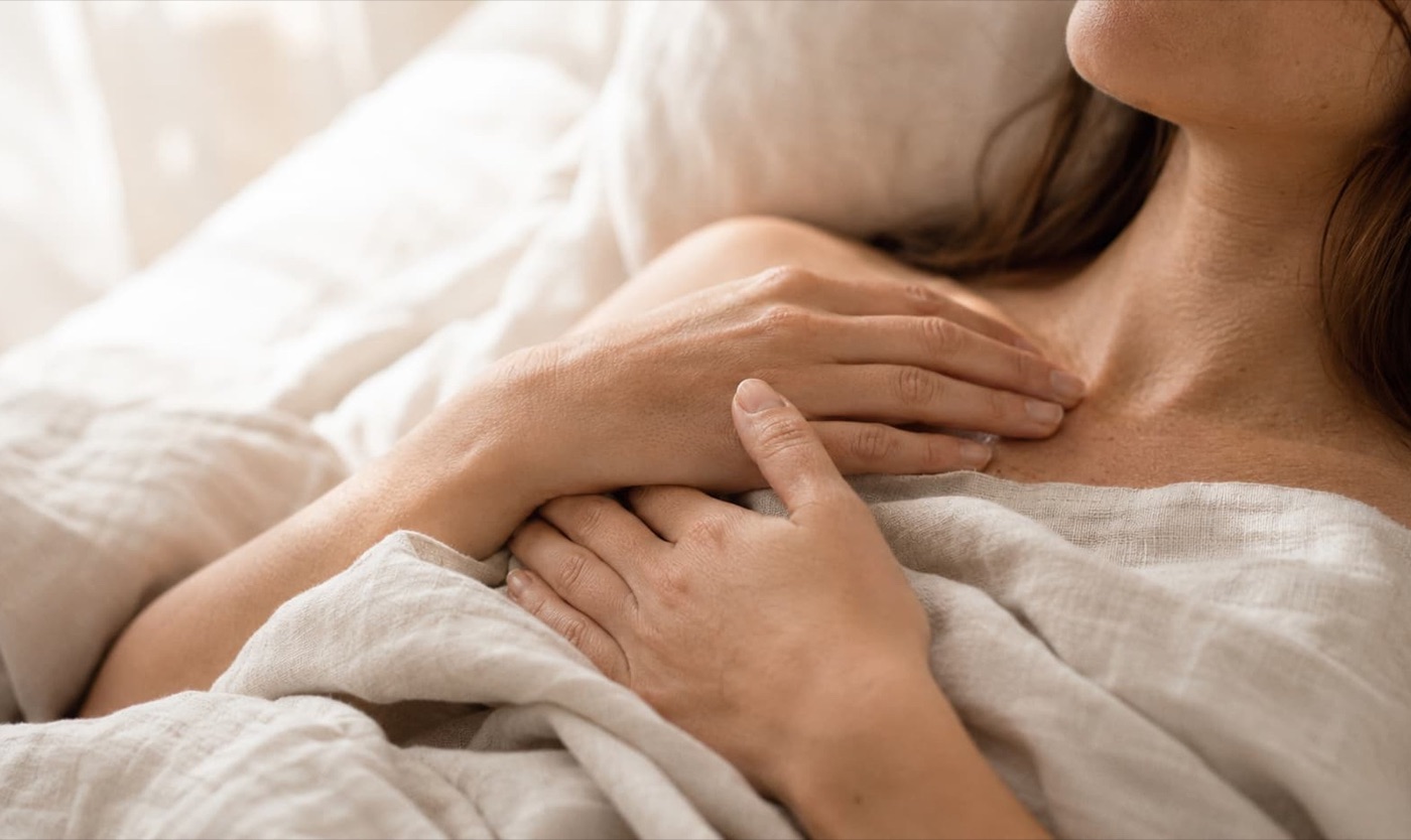 Nahaufnahme von Händen, die sanft auf der Brust ruhen – Körperwahrnehmung und Hinhören als Grundlage der Libido