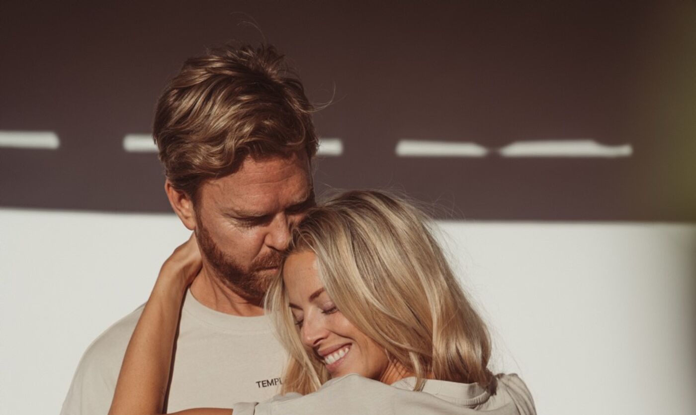 A couple embracing in sunlight, he kisses the top of her head and she smiles, the repair that follows a hard conversation