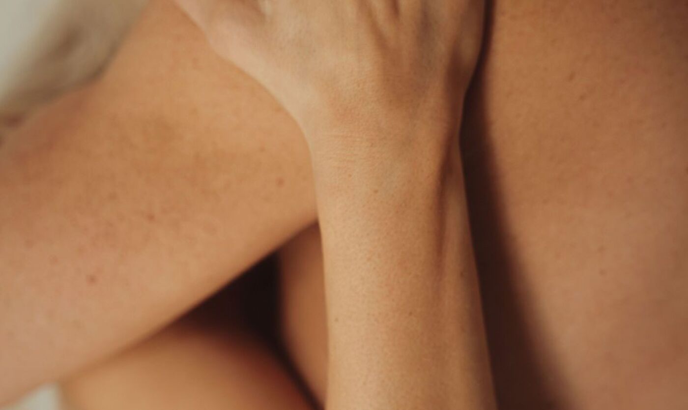 Close-up of crossed legs in warm, soft light, the quiet body sensation responsive desire builds from